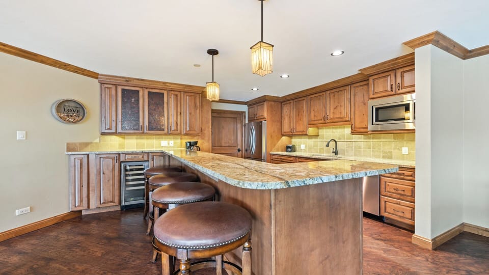 You'll love gathering in this beautifully designed kitchen featuring warm wood cabinetry, granite countertops, stainless steel appliances, and a spacious island with seating—perfect for cooking, dining, and making memories together.