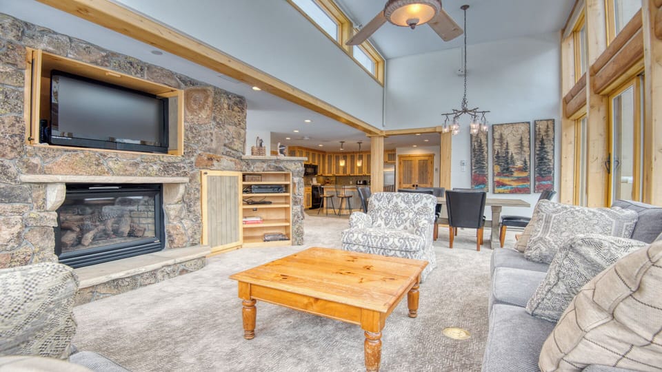 Unwind in your spacious open-concept retreat, where rustic stone walls, soaring ceilings, and cozy fireside seating invite you to relax and connect with mountain charm and modern comfort.