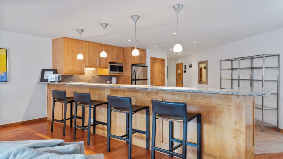Gather around this spacious kitchen island for morning coffee or casual meals. The sleek granite countertop and modern bar seating create a warm social hub in your mountain retreat.