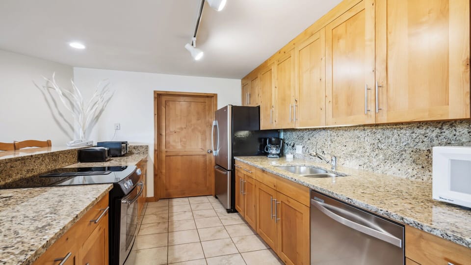 Your fully equipped kitchen features granite countertops, stainless steel appliances, and warm wood cabinetry—perfect for preparing home-cooked meals during your stay.