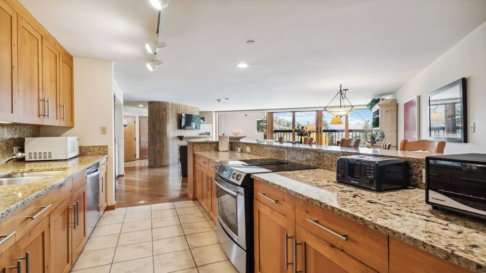 Step into your spacious open-concept kitchen and living area, where warm wood cabinetry, granite countertops, and stainless appliances set the stage for memorable meals and relaxed evenings together.