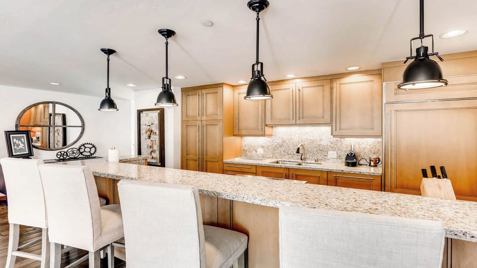 Your spacious kitchen awaits, featuring granite countertops, warm wood cabinetry, and modern pendant lighting—perfect for cooking together or sharing morning coffee at the breakfast bar.