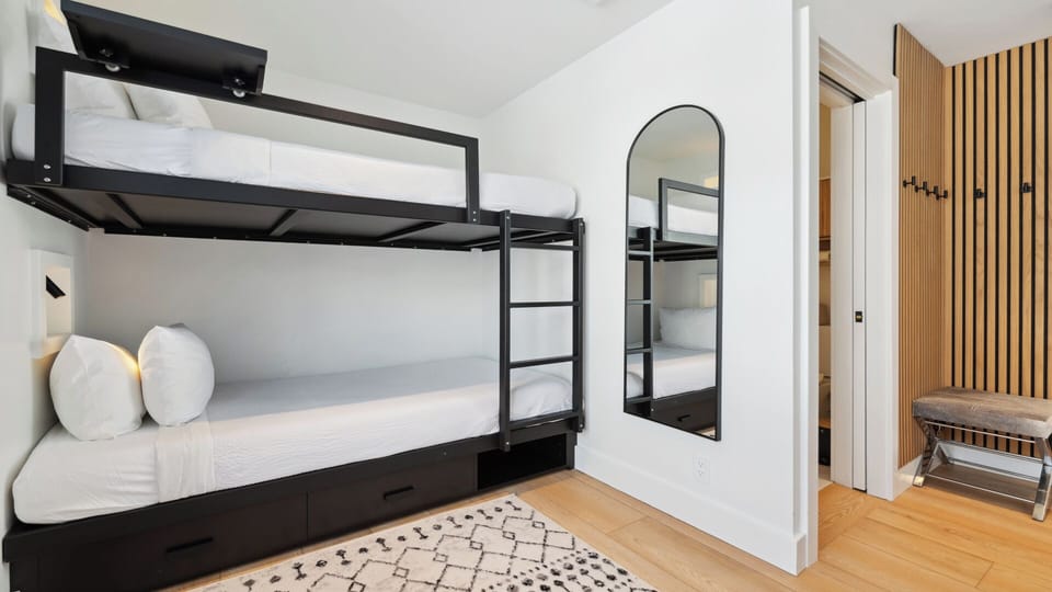 Sleep soundly in this bright, modern bunk room with stylish black metal frames and cozy white linens. Your group will love the efficient layout and thoughtful design touches.