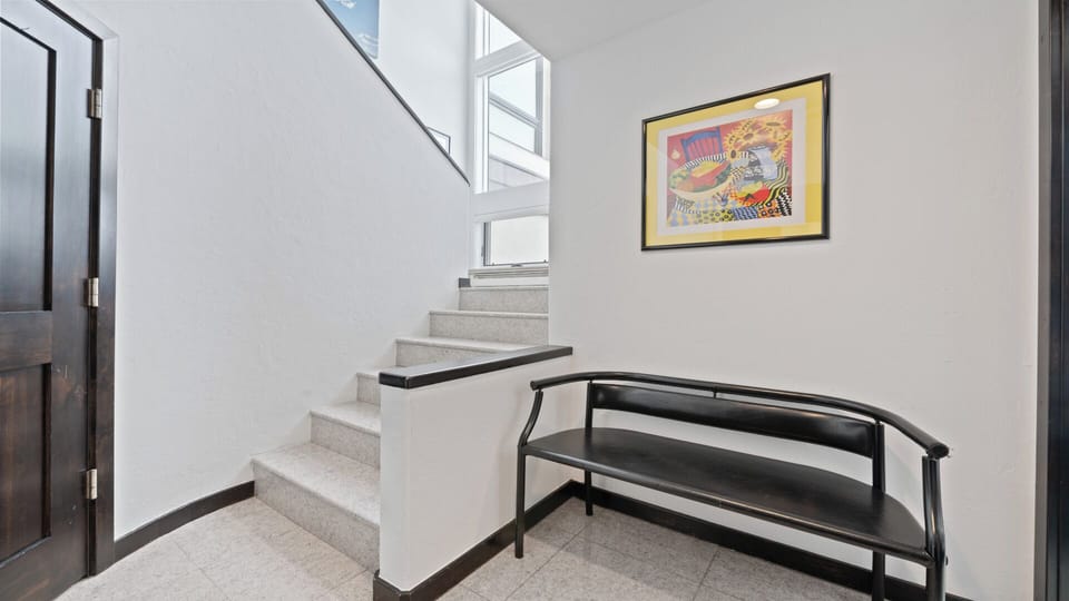 A bright, modern entryway features a welcoming staircase with sleek lines, a cozy bench to slip off your shoes, and cheerful artwork that instantly makes you feel at home.
