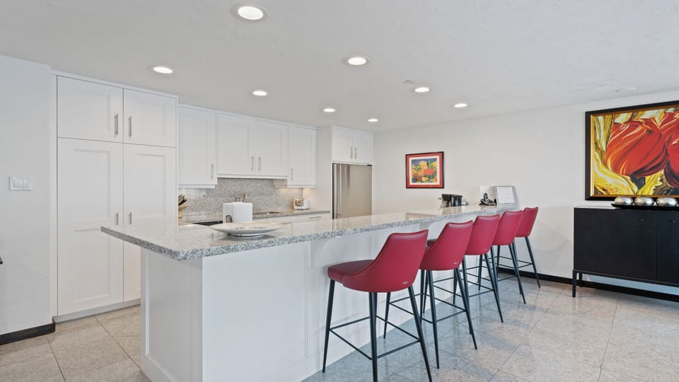 Your spacious kitchen features bright white cabinetry, granite countertops, and a welcoming island with seating for four—perfect for morning coffee or casual meals together.