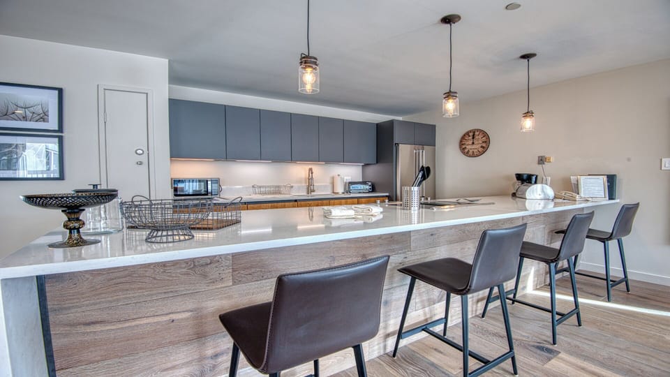 Gather around the spacious kitchen island where modern style meets comfort. Sleek pendant lights illuminate gleaming countertops, stainless steel appliances, and bar seating—perfect for morning coffee or evening meals together.