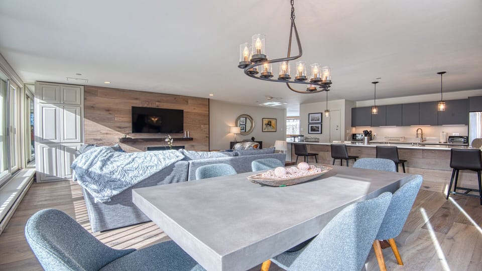 Settle into this expansive open living space where modern design meets comfort. Enjoy your favorite shows, share meals at the sleek dining table, or prepare feasts in the fully-equipped kitchen—all under warm lighting.