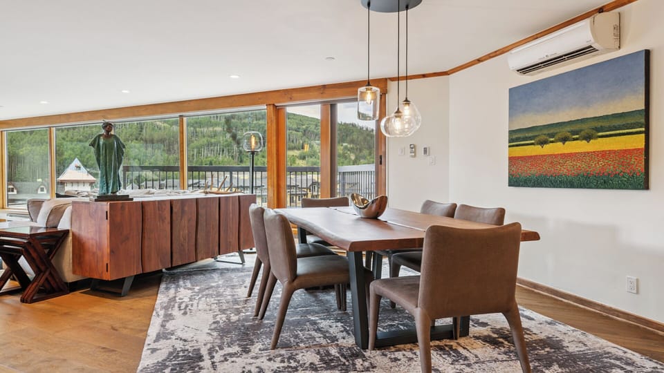 Gather around this elegant dining table where natural light pours through expansive windows, framing stunning mountain views while you share meals and create memories together.