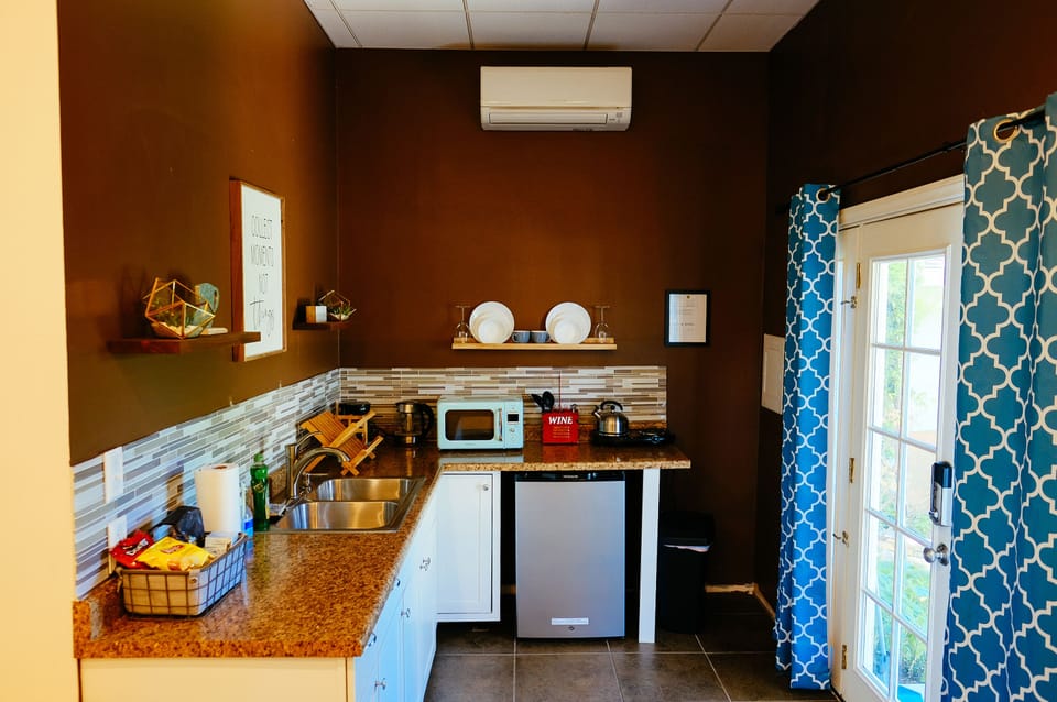 Kitchenette with coffee maker, microwave, dual hot plates, and dishware.