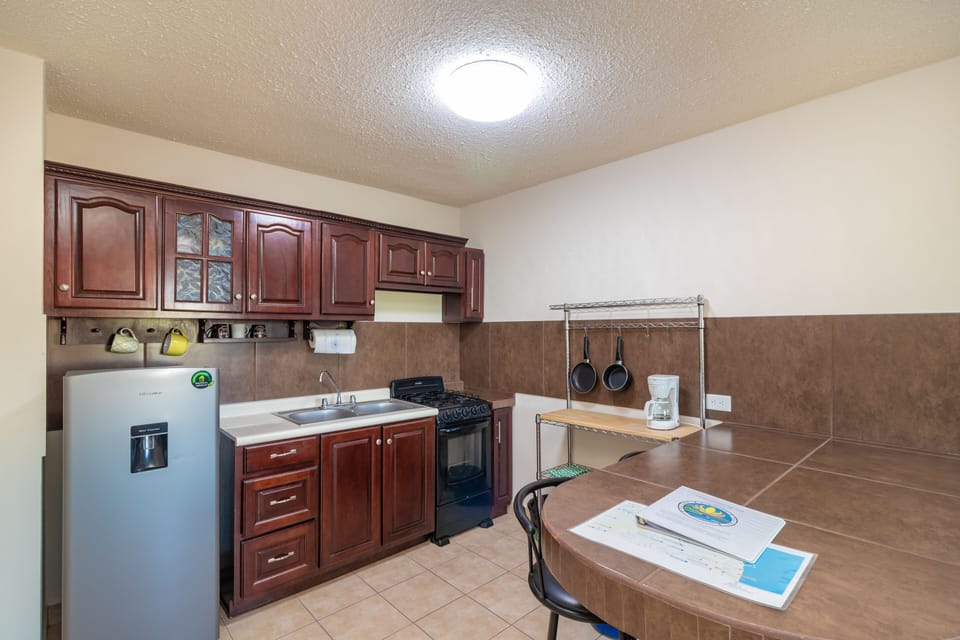 Kitchen has built-in bar, fridge, stove, pots, pans, dishes needed for meals.