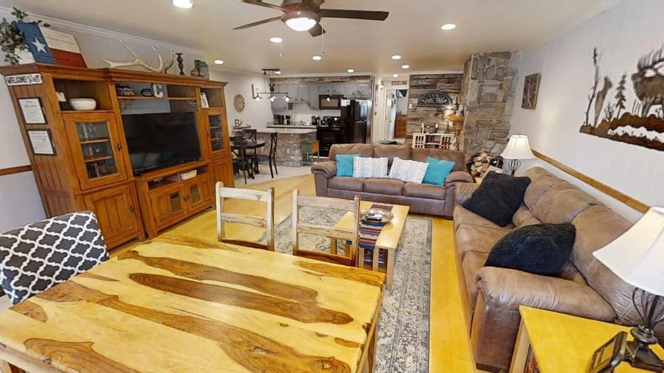 Unwind in your spacious living area with rustic Texas charm, featuring plush sofas, a stone fireplace, and an open kitchen—perfect for gathering after a day of adventure.