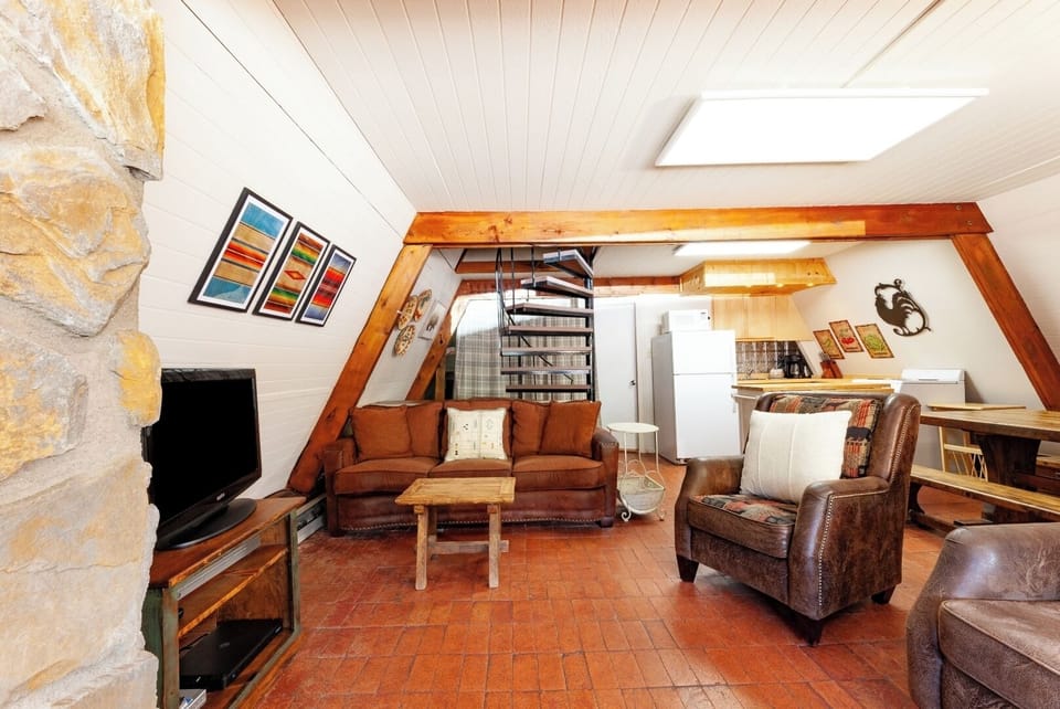 Unwind in your cozy living space with vaulted ceilings, rustic beams, and plush leather seating—a warm retreat with charming character and room to relax.