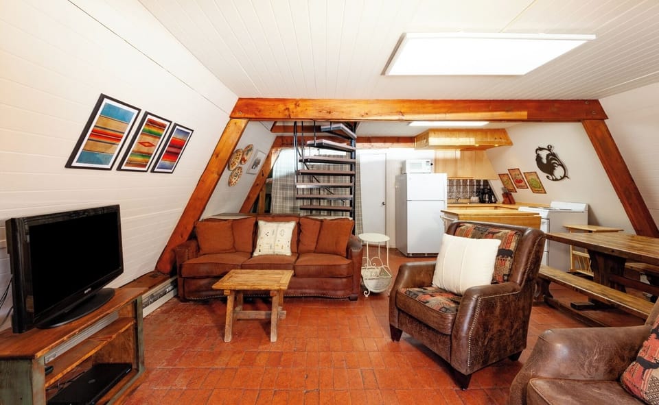 Unwind in your cozy loft-style retreat with leather seating, spiral stairs to the upper level, and a fully equipped kitchenette—your home away from home.