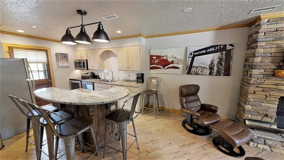 Gather around the kitchen island for meals or unwind in your cozy leather recliner by the stone fireplace. Modern appliances and mountain-themed décor set the perfect tone for your alpine getaway.