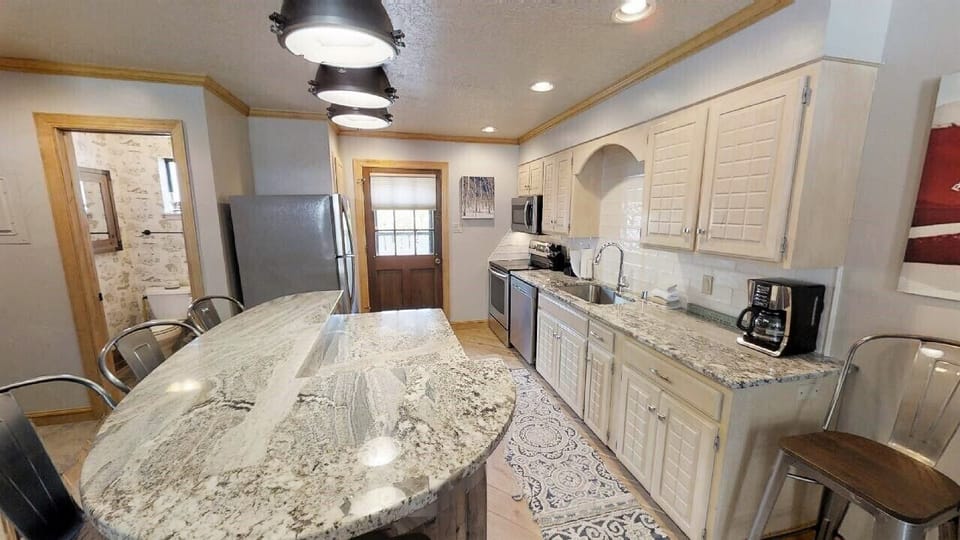 Gather around this spacious kitchen with gleaming granite counters, modern appliances, and warm industrial lighting—perfect for creating memorable meals together during your stay.