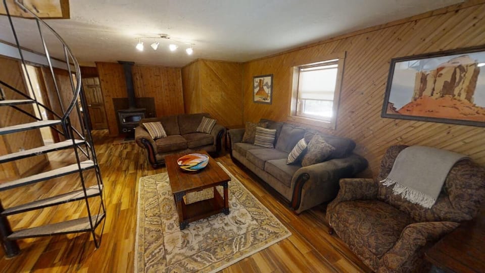 Sink into plush seating in this warm, wood-paneled living room where rustic charm meets comfort. Gather around the coffee table or unwind on cozy sofas after exploring nearby attractions.