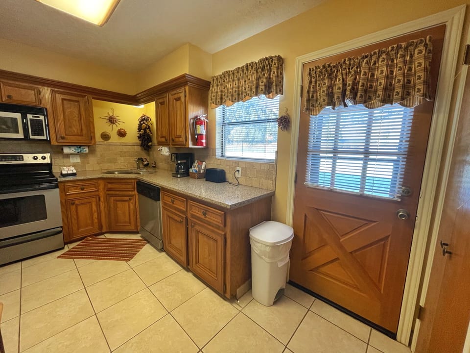 A fully-equipped kitchen with oak cabinetry, granite countertops, and modern appliances awaits your culinary adventures, all bathed in natural light from two cheerful windows.