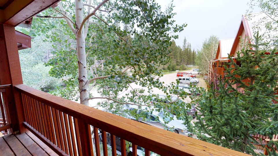The property is situated in a wooded mountain area with parking and neighboring cabins visible nearby, providing a peaceful natural retreat setting.