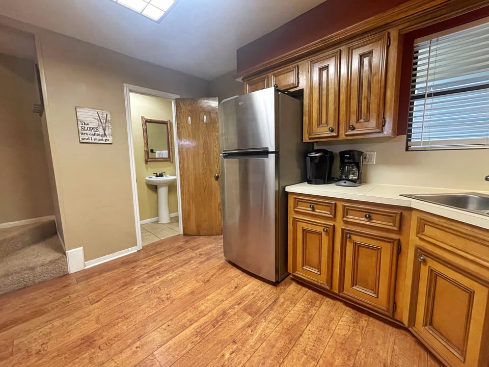 Your fully equipped kitchen features stainless steel appliances, warm wood cabinetry, and plenty of counter space for preparing meals. Natural light streams in from above, creating a bright and welcoming space for your stay.