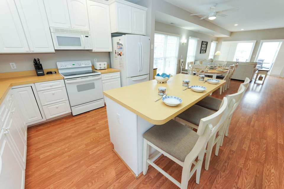 12 Dune Road - Tower Shores - Kitchen Island View - A view of the kitchen island featuring a light wood countertop and bar stool seating, looking outward toward the living spaces.