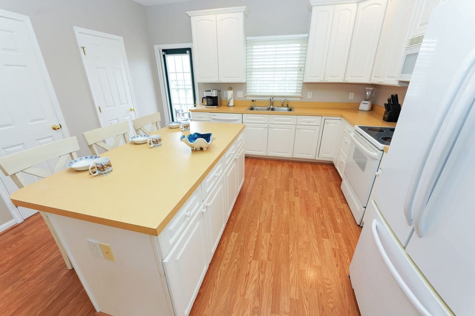 12 Dune Road - Tower Shores - Kitchen and Counter Space View - A bright kitchen angle highlighting the white cabinetry, light countertops, and warm hardwood flooring.