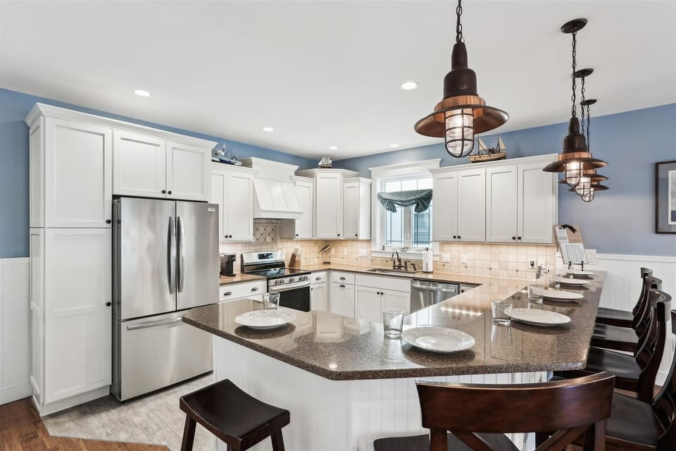 221 Wellington Parkway Gourmet Kitchen with Stainless Steel Appl - A modern kitchen showcasing white cabinetry against soft blue walls, featuring a stainless steel French door refrigerator and a built-in microwave.