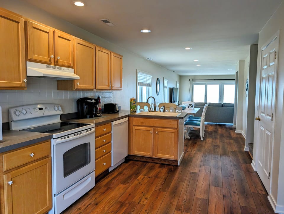 38901 Bunting Avenue Kitchen with Oak Cabinets and Island - A well-lit kitchen featuring honey-toned oak cabinetry, white appliances, and a center island with a light countertop.