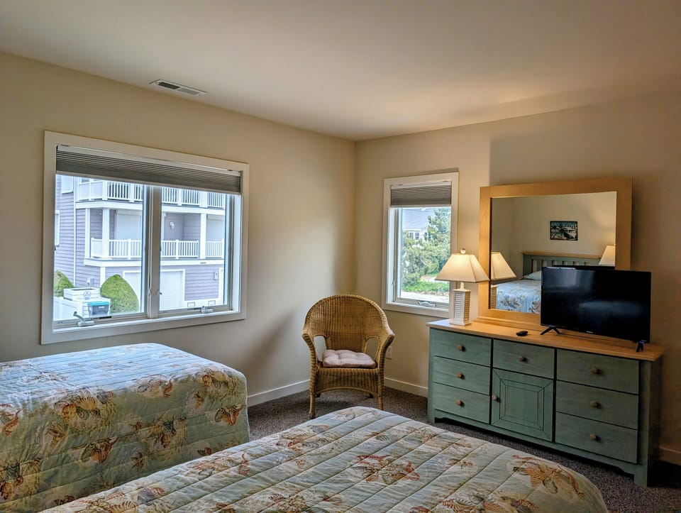 38901 Bunting Avenue Guest Bedroom Perspective with Wicker Seati - A corner view of the guest bedroom showcasing the proximity of the dresser to the windows and the entry door.