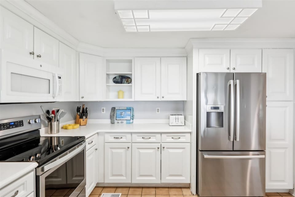 35 Kings Grant, Fenwick Island-Kitchen - Modern kitchen with white cabinets, stainless steel refrigerator and stove, and recessed lighting.