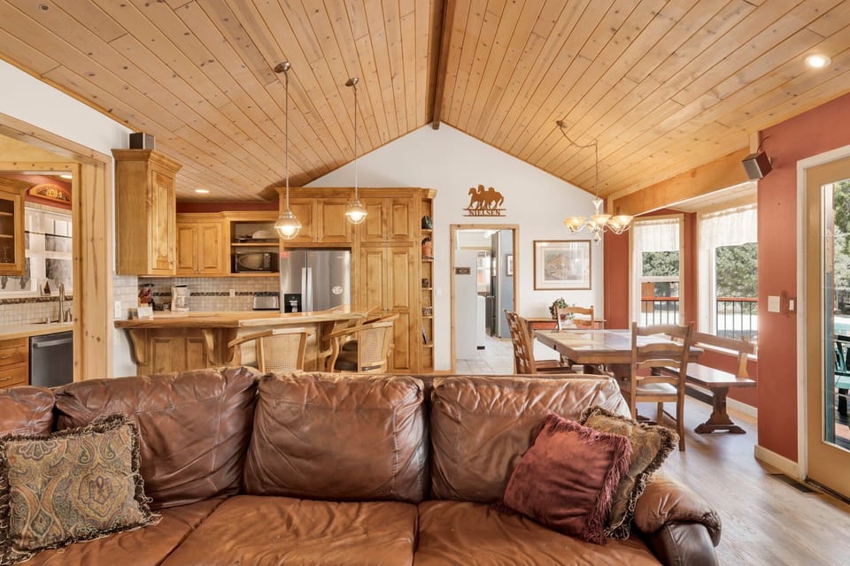 Cozy mountain living room with wood ceilings, fireplace, comfy seating, and smart TV—perfect for relaxing evenings, movie nights, and warm cabin vibes after outdoor adventures.