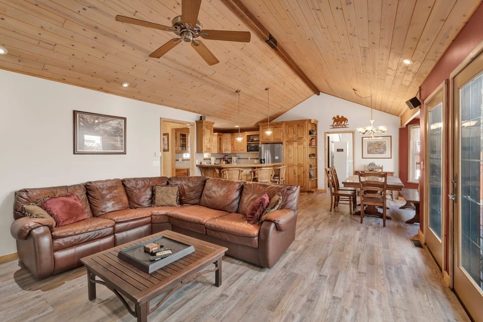 Cozy mountain living room with wood ceilings, fireplace, comfy seating, and smart TV—perfect for relaxing evenings, movie nights, and warm cabin vibes after outdoor adventures.