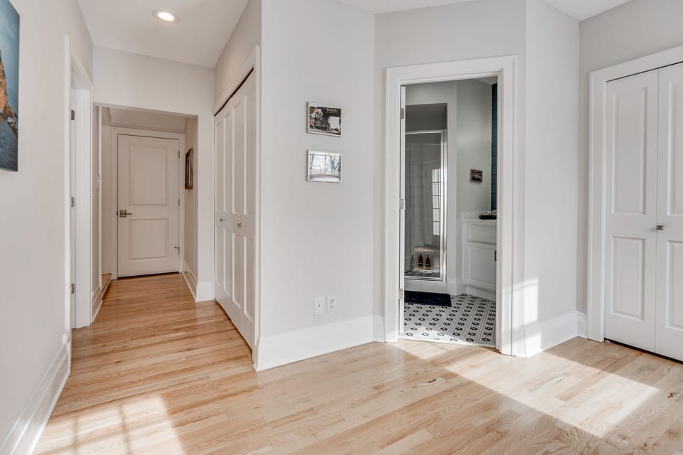Step into your bright hallway with gleaming hardwood floors and crisp white walls, where thoughtful details and a peek into the stylish bathroom await.