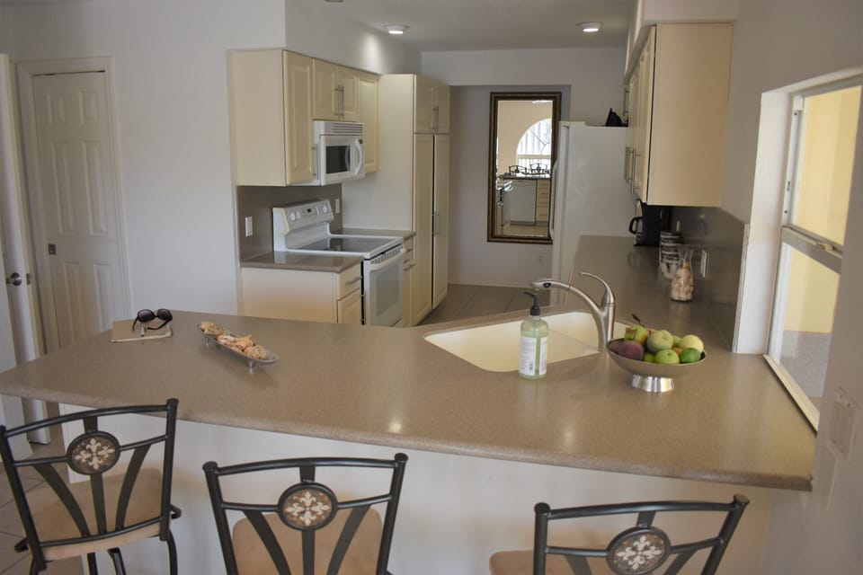 Corian breakfast bar w/ seating for three & passing window to outdoor kitchenet