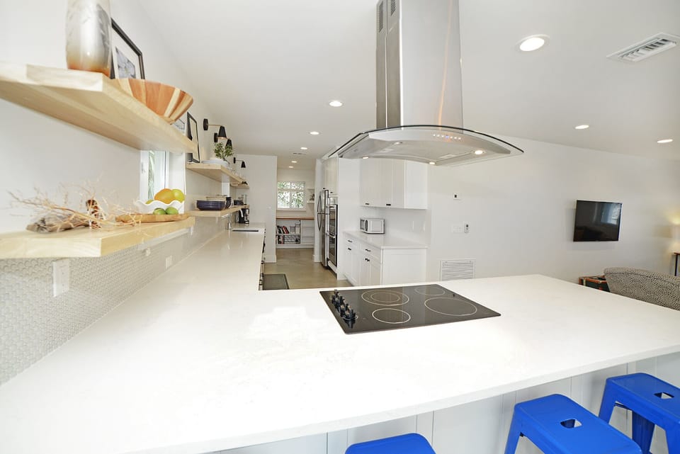 Uber cool floating wood shelves in the kitchen, quartz counters, electric stove.