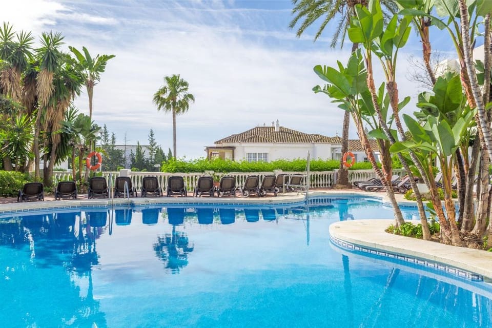 Dive into the crystal blue waters of a pool that invites leisurely days under the open sky amidst tropical palms.