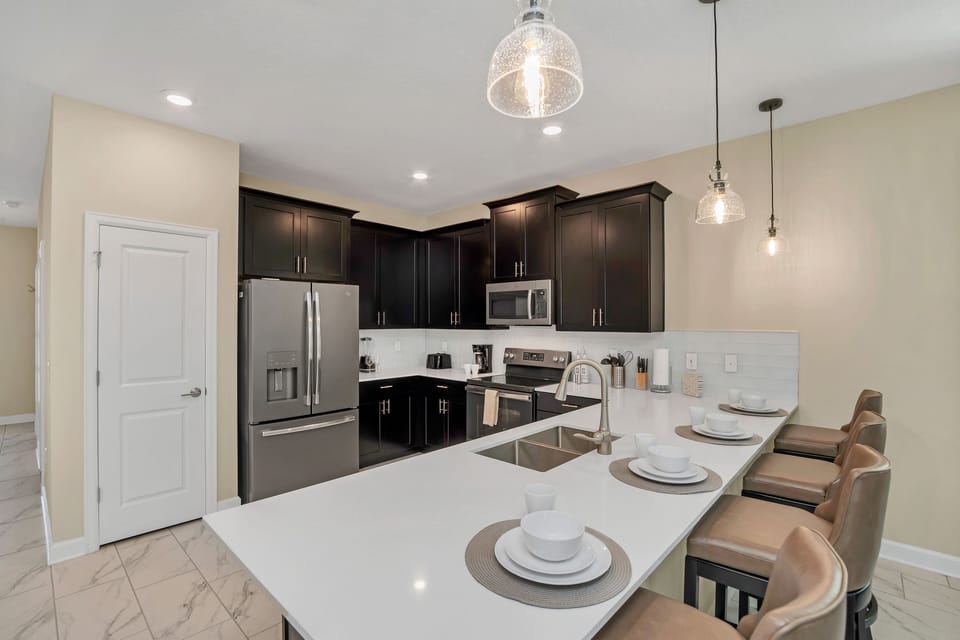 Spacious kitchen with dark cabinetry and a inviting island for gathering - Fully equipped and perfect for entertaining, with seating for casual meals or conversations - Modern lighting and polished finishes make this kitchen a chef’s dream