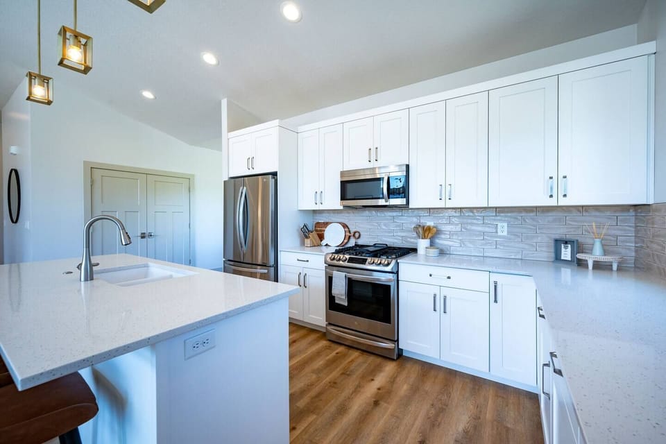 The gourmet kitchen features an island with seating for four and is equipped with stainless steel appliances, including a microwave, gas stove, and spacious refrigerator.