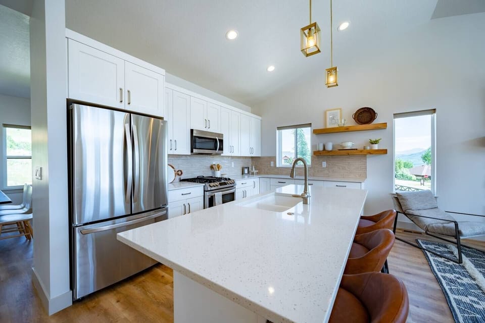 With its modern lighting, windows, quartz countertops, and stunning backsplash, the kitchen makes preparing dinner a truly enjoyable experience.