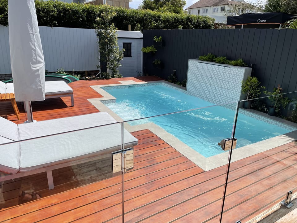Resort style sun deck with 2 double sun lounges and resort umbrella. Heated pool