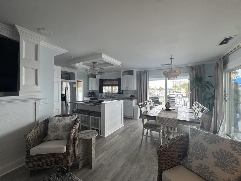 Open-concept kitchen and dining area with white cabinetry, gray wood floors, and sliding doors to a balcony.
