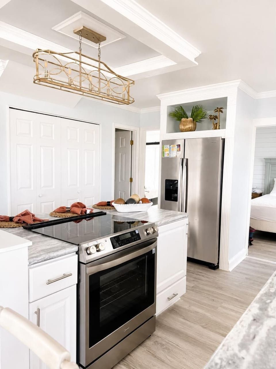 Marble-patterned countertops surround a stainless steel stove and refrigerator in the bright kitchen.