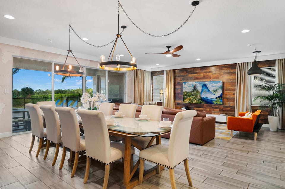 - Elegant dining room with seating for a large group gathering  
- Stylish lighting and glass table enhance the modern atmosphere  
- Open layout connects kitchen and living room for easy hosting