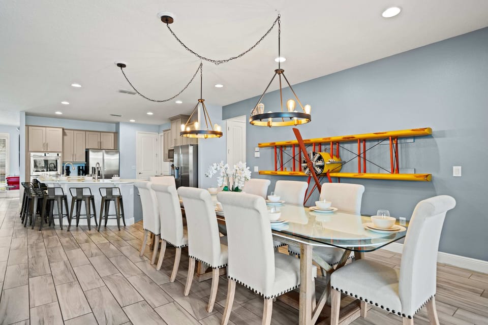 - Open dining and kitchen area with seating for large gatherings  
- Elegant lighting fixtures and airplane wall decor for style  
- Spacious setup connects to modern kitchen for easy hosting