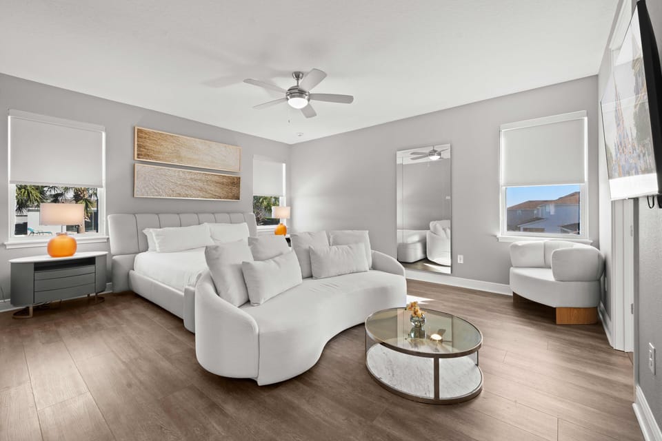 - Bedroom with modern furniture and white elegant design  
- King bed with cozy sitting area and large wall mirror  
- Orlando vacation rental with bright family bedrooms