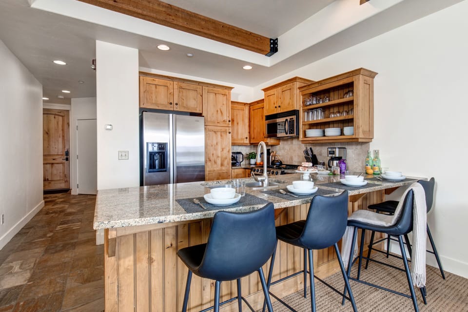 Fully Equipped Kitchen with granite countertops, stainless steel appliances, built-in water and ice dispenser, and bar seating for four