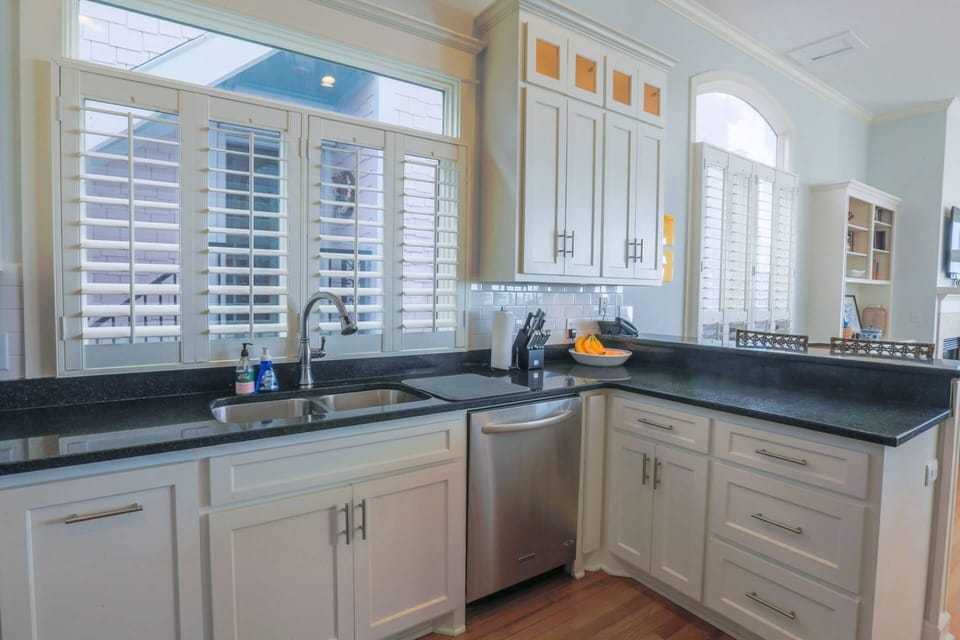 The kitchen for A Golden Sunrise features white cabinetry, a white tiled backsplash and stainless steel appliances.