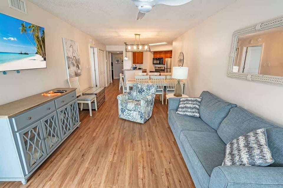 - Open concept living room with dining and kitchen view   - Comfortable sofa and chairs perfect for family stays   - Coastal décor and bright layout with smart TV access