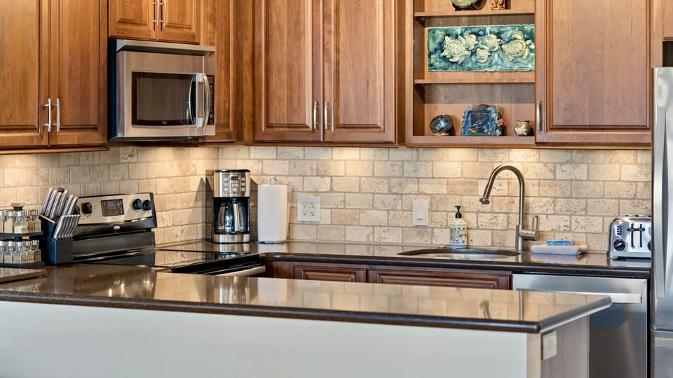 Kitchen with granite counters, stone backsplash and under cabinet lighting.