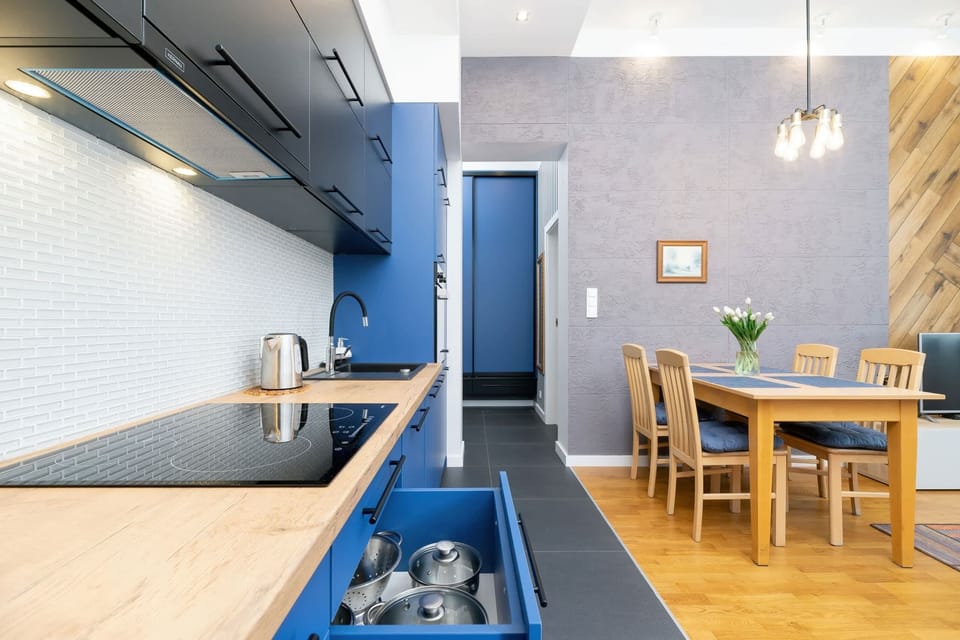 A dining area near the kitchen, with a wooden table, chairs, and ample lighting.