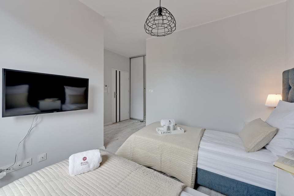 A modern twin bedroom with two single beds and a centrally placed TV, perfect for relaxing and unwinding.